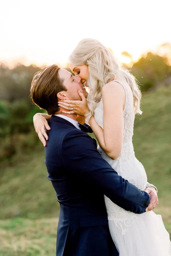 bride and groom kissing in maleny near the maleny manor while he lifts her into the air.