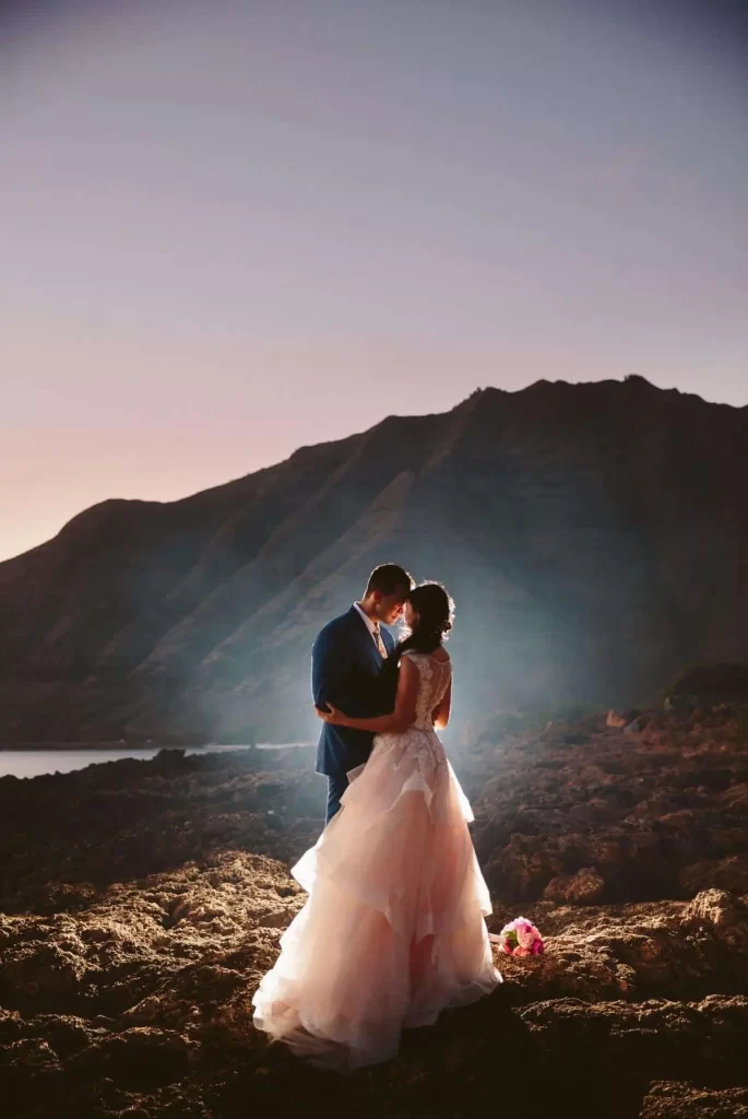 Bride and groom kissing at sunset on a beach in Oahu, Hawaii.