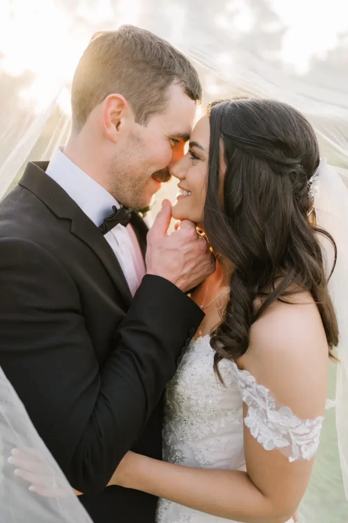 Intimate wedding portrait of a couple under the veil in soft golden light