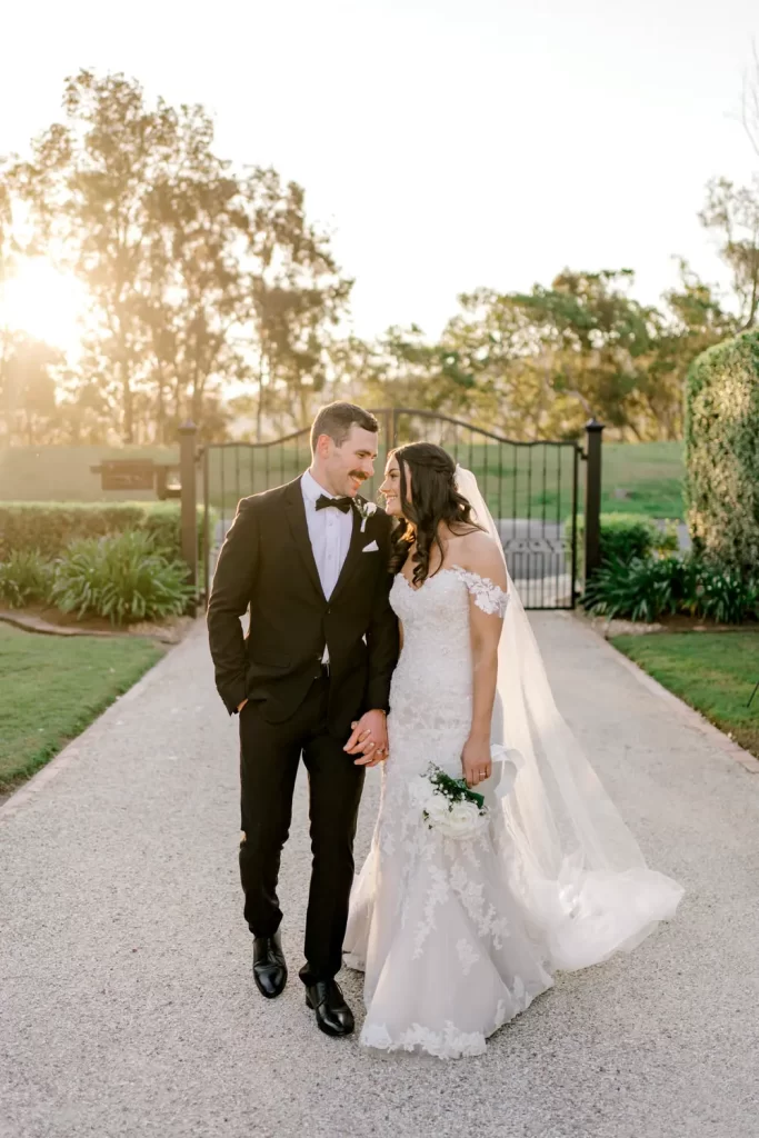 bride and groom walking down the driveway in northern nsw looking at each other as they celebrate their wedding day.