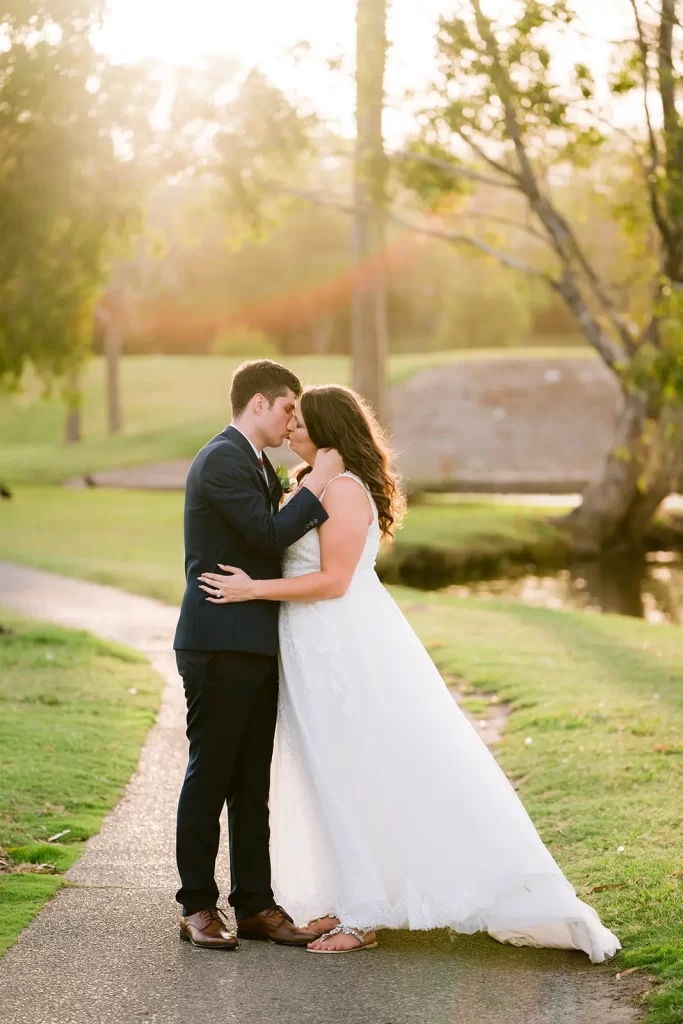 Bride and groom walking and kissing along the trails at the parkwood golf course